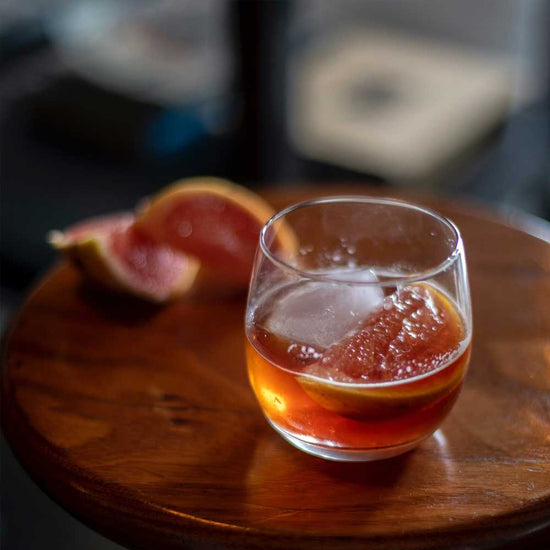 Cold brew coffee Negroni in a round glass with ice and a slice of pink grapefruit