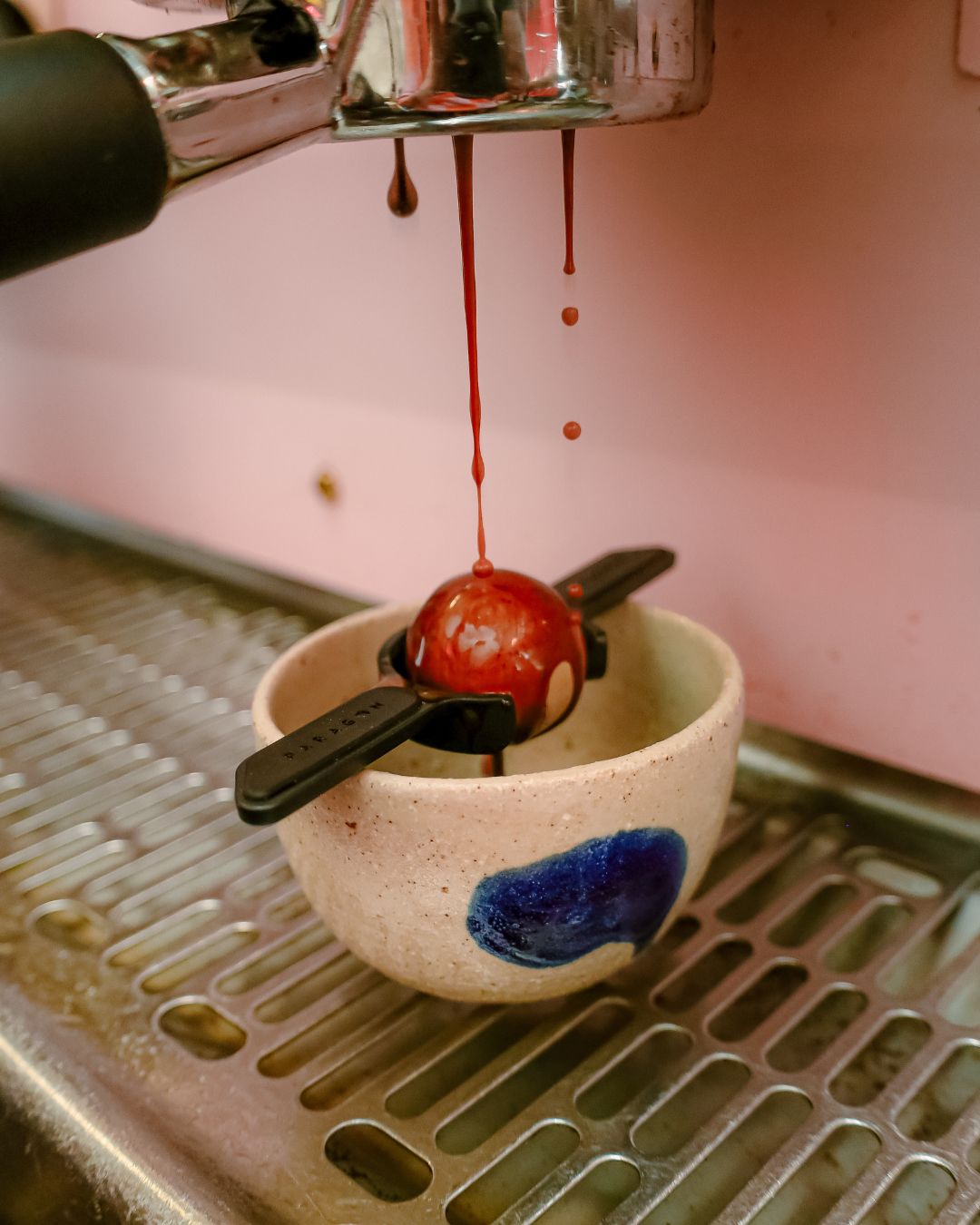 espresso being extracted on a pink espresso machine using golden ball into a handmade cup