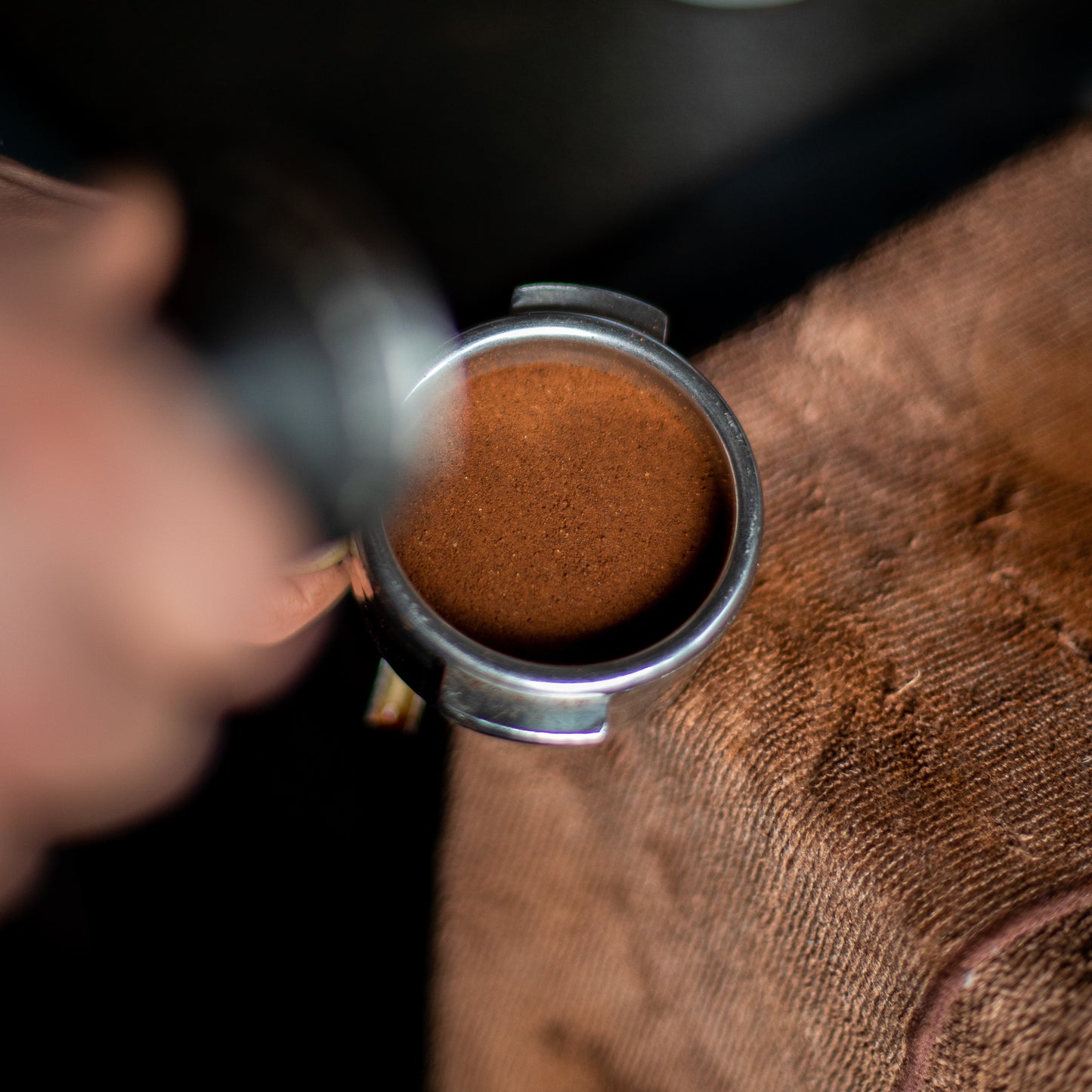 A picture of a espresso machine portafilter with ground coffee inside flat after being tamped 