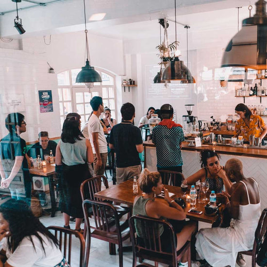 People in a busy cafe standing up to order at a counta