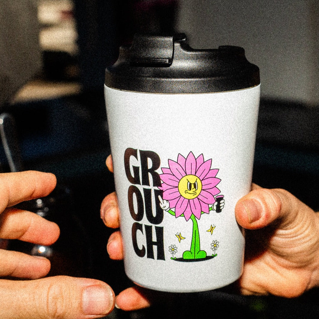 A hand passing a white stainless steel travel mug keep cup to another hand